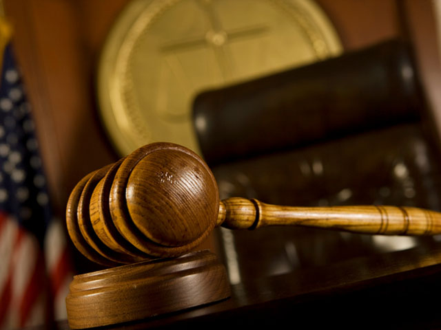 A gavel is shown in front of a judge's bench, seal, and flag in a courtroom for criminal defense.